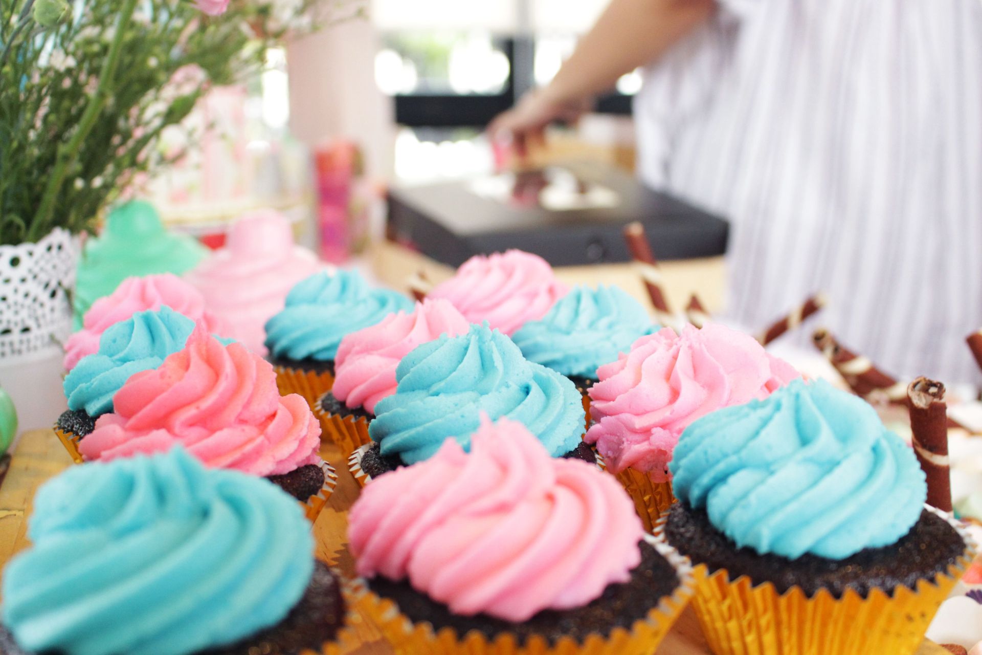 Vibrant pink and blue frosted cupcakes displayed on a table, ideal for dessert enthusiasts.
